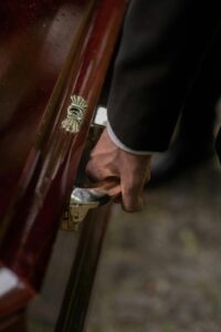 Person in Black Suit Jacket Carrying a Coffin